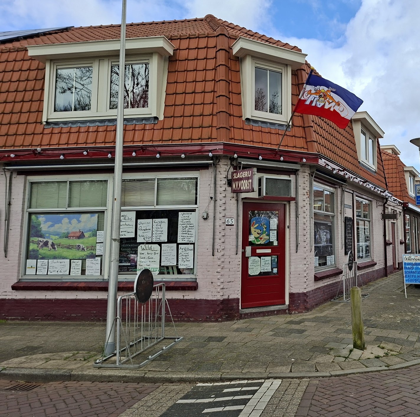 Het uithangbord Slagerij W.V. Voorst boven de rode deur, met het lampjessnoer langs de gevel